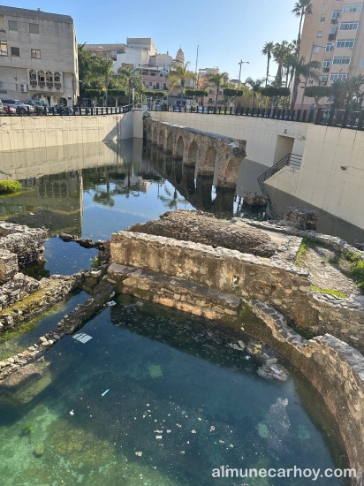 estos de termas y tramo del acueducto romano de La Carrera parcialmente inundados, con el agua estancada reflejando los arcos y los edificios cercanos en Almuñécar.